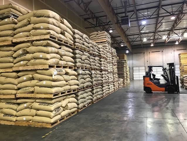 Pallets of green coffee sacks stacked the length of a warehouse.